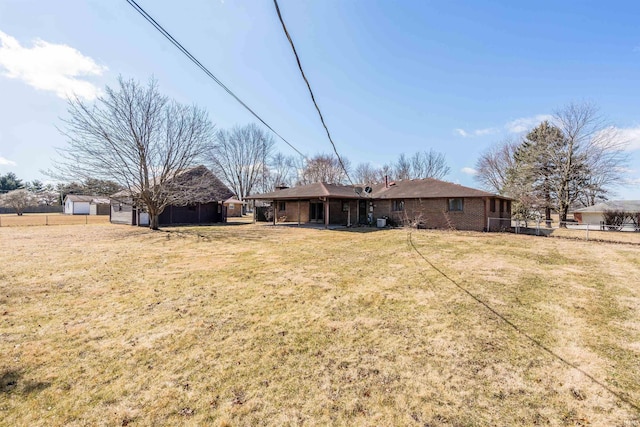 back of house with brick siding, fence, and a yard