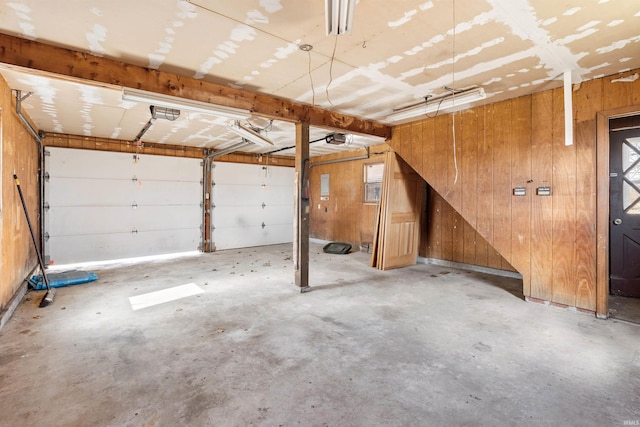 garage with a garage door opener and wooden walls