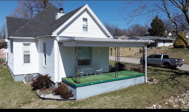 back of property with a yard, a shingled roof, a chimney, and cooling unit