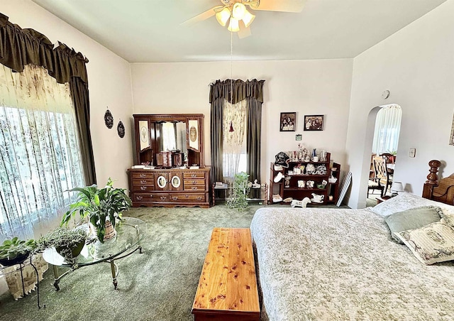 carpeted bedroom with ceiling fan and arched walkways