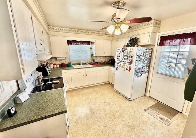 kitchen featuring tasteful backsplash, dark countertops, a sink, white appliances, and under cabinet range hood