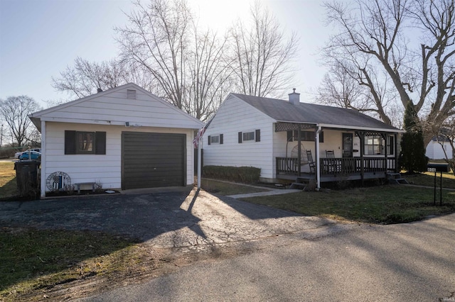 view of front facade featuring driveway, a garage, a chimney, an outdoor structure, and a front lawn