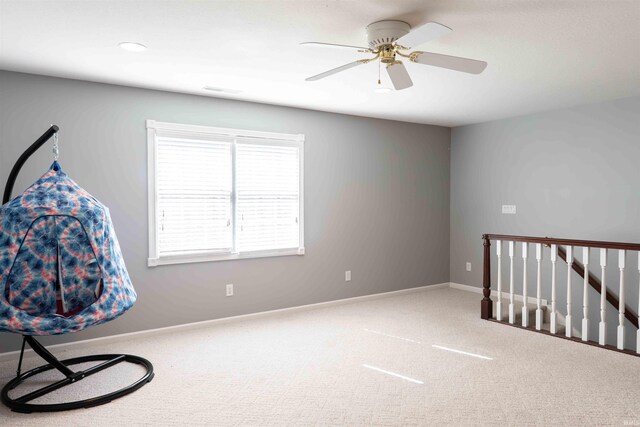 interior space with carpet, baseboards, ceiling fan, and an upstairs landing