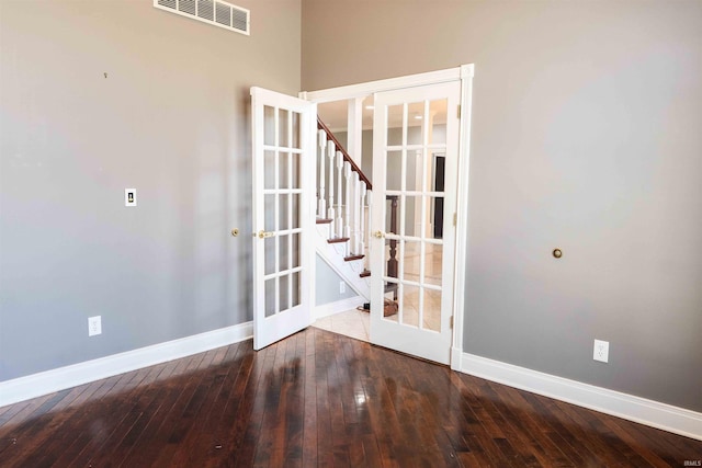 empty room with french doors, visible vents, baseboards, and hardwood / wood-style flooring