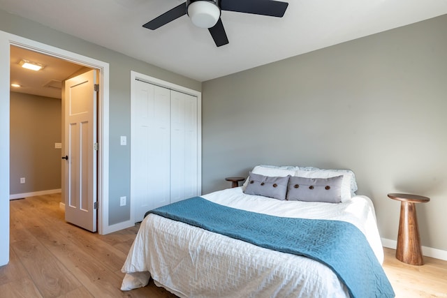 bedroom with a closet, wood finished floors, a ceiling fan, and baseboards