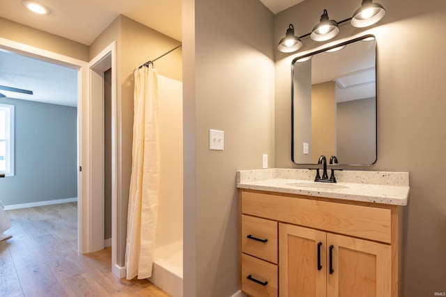 full bathroom with a shower with curtain, vanity, baseboards, and wood finished floors