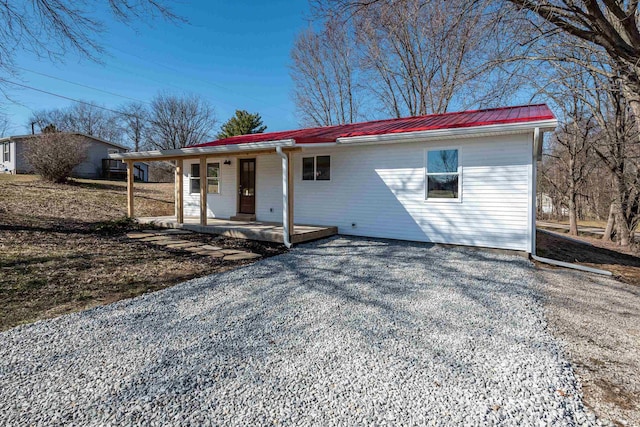 single story home with a porch, metal roof, and driveway