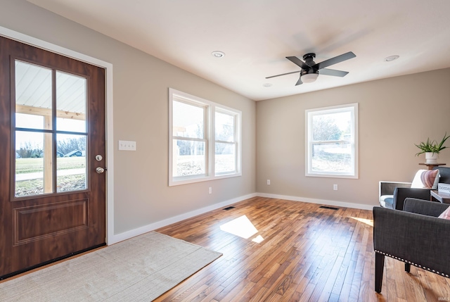 entryway featuring hardwood / wood-style floors, a ceiling fan, visible vents, and baseboards