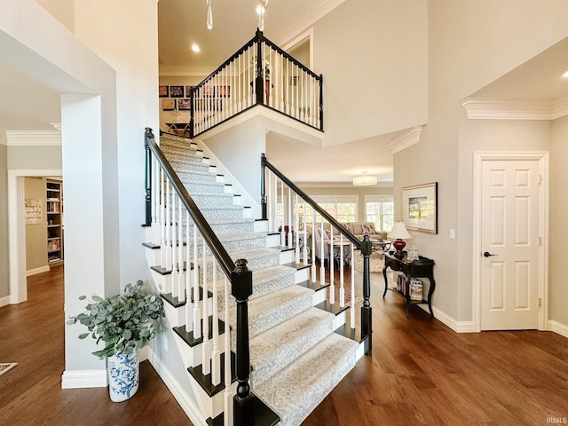 stairway featuring ornamental molding, a high ceiling, and wood finished floors