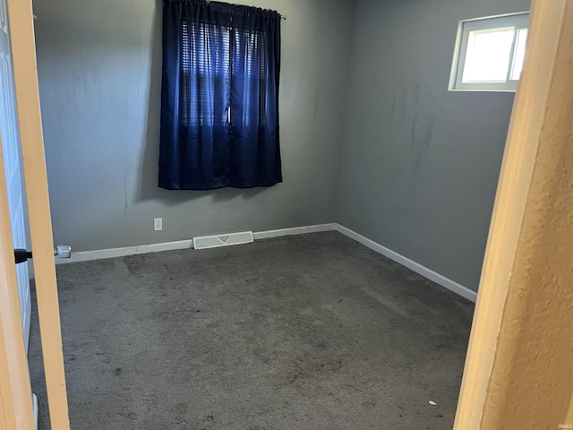 empty room with dark colored carpet, visible vents, and baseboards