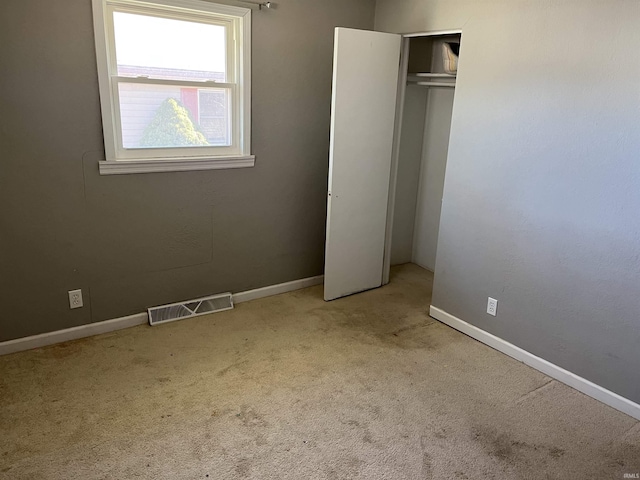 unfurnished bedroom featuring carpet floors, a closet, visible vents, and baseboards