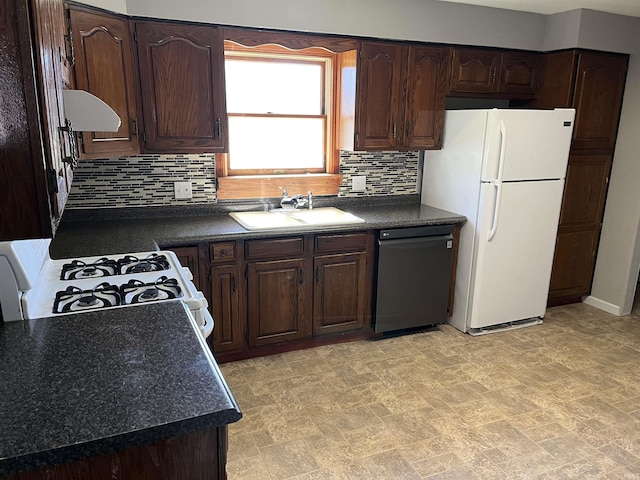 kitchen with dark countertops, white appliances, dark brown cabinetry, and a sink