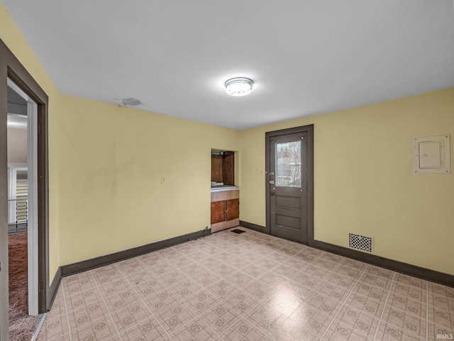 spare room with electric panel, visible vents, baseboards, and light floors