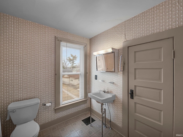 half bath featuring tile patterned floors, baseboards, toilet, and wallpapered walls