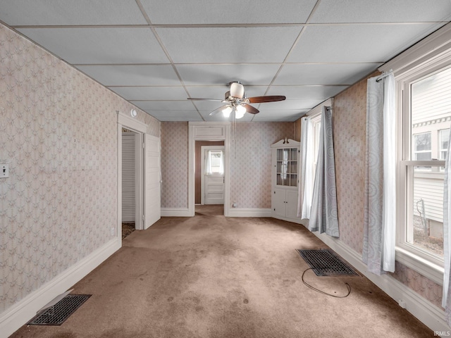 carpeted empty room with a drop ceiling, visible vents, baseboards, and wallpapered walls