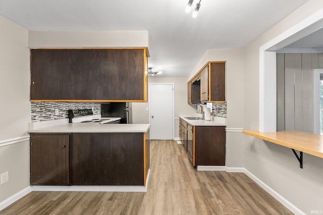 kitchen featuring tasteful backsplash, dark brown cabinets, light countertops, electric stove, and light wood-style floors