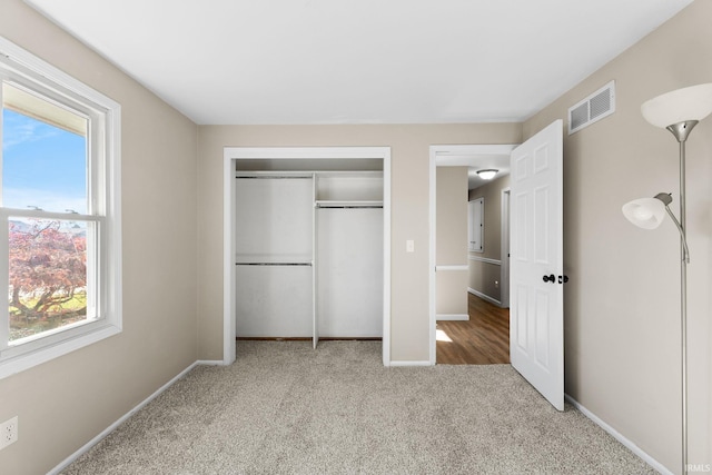 unfurnished bedroom with multiple windows, carpet flooring, visible vents, and a closet