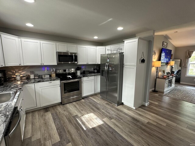 kitchen with appliances with stainless steel finishes, white cabinetry, and wood finished floors