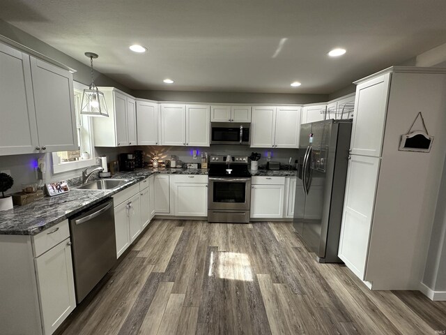 kitchen with a sink, white cabinets, wood finished floors, and stainless steel appliances