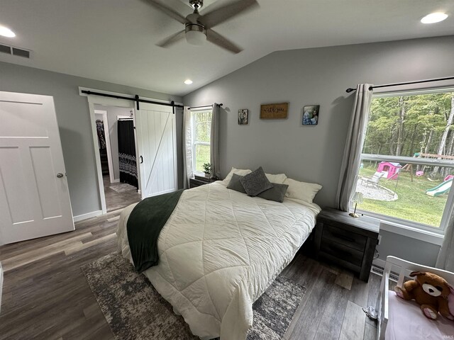 bedroom featuring visible vents, wood finished floors, a barn door, ceiling fan, and vaulted ceiling