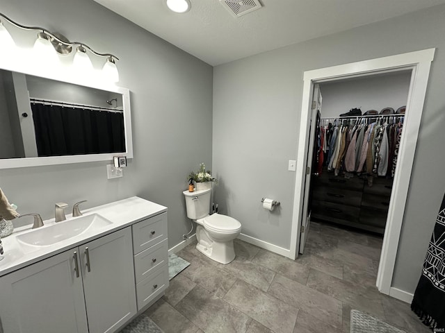 full bathroom with a spacious closet, visible vents, baseboards, toilet, and vanity