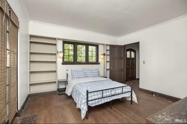 bedroom featuring crown molding, baseboards, and wood finished floors