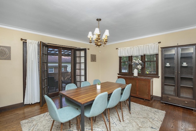 dining room featuring baseboards, an inviting chandelier, hardwood / wood-style floors, and crown molding