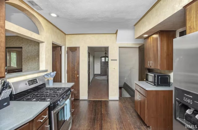 kitchen featuring dark wood-style flooring, light countertops, appliances with stainless steel finishes, a textured ceiling, and brown cabinets