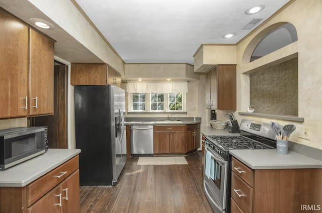 kitchen with visible vents, brown cabinets, dark wood finished floors, appliances with stainless steel finishes, and light countertops