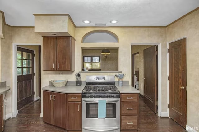 kitchen with light countertops, dark wood-type flooring, stainless steel gas range, and ornamental molding