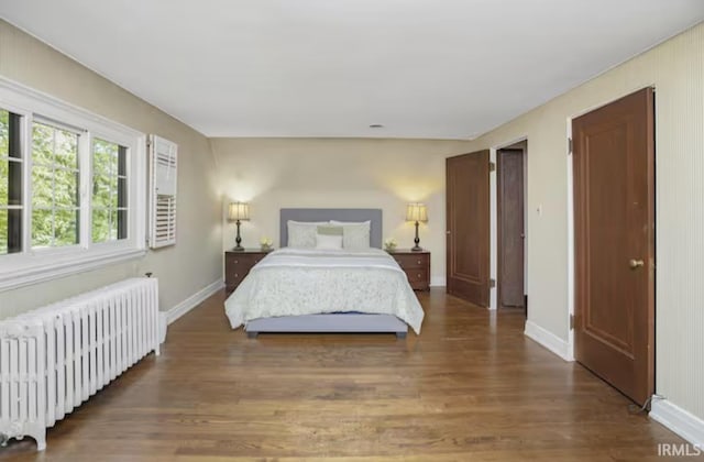 bedroom featuring radiator heating unit, wood finished floors, and baseboards