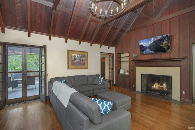 living area featuring wood finished floors, a fireplace with flush hearth, wood ceiling, beamed ceiling, and a notable chandelier