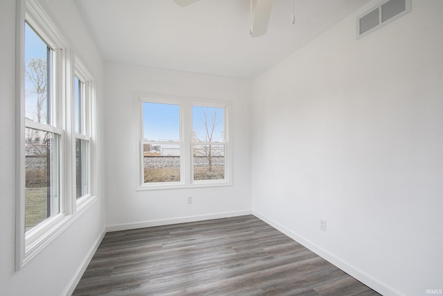 empty room with visible vents, baseboards, and dark wood-style floors