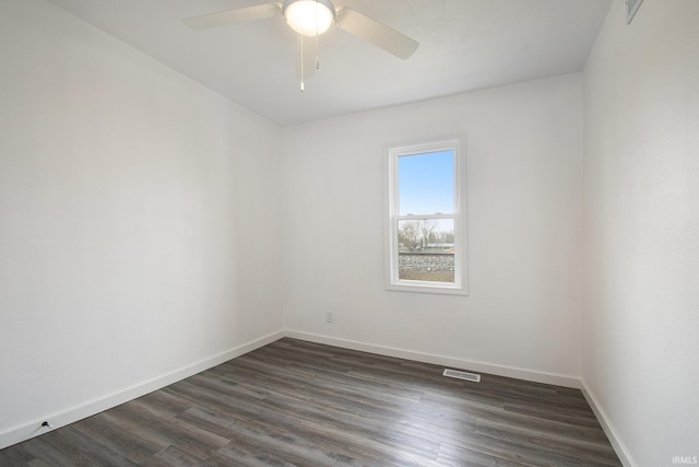 spare room featuring ceiling fan, visible vents, baseboards, and dark wood finished floors