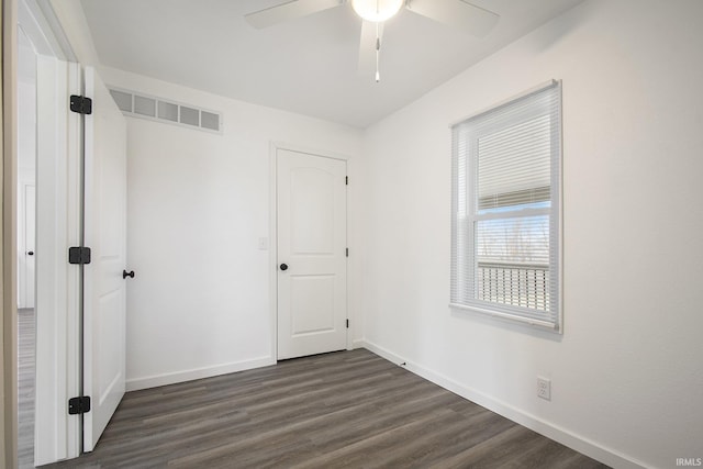 unfurnished bedroom featuring dark wood-style floors, visible vents, ceiling fan, and baseboards