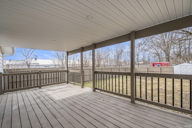 wooden deck featuring an outbuilding, a lawn, a fenced backyard, and a shed