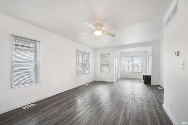 spare room with visible vents, baseboards, dark wood-type flooring, and a ceiling fan