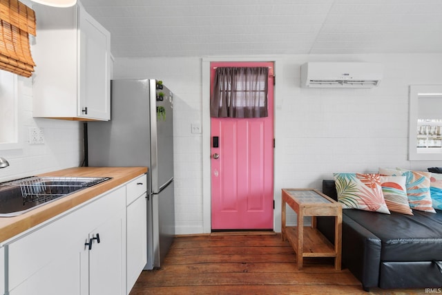 kitchen featuring a sink, light countertops, a wall unit AC, white cabinets, and dark wood-style flooring