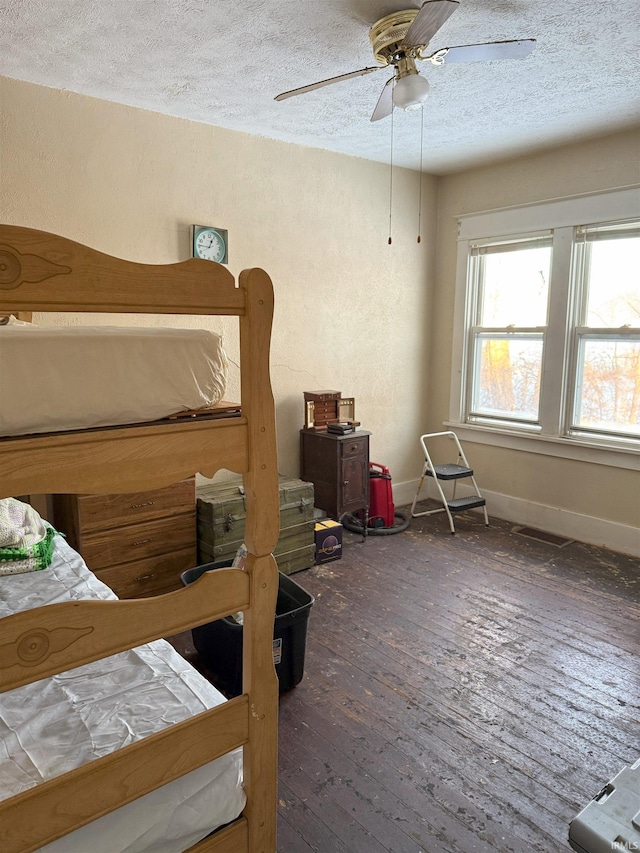 bedroom with ceiling fan, hardwood / wood-style flooring, baseboards, and a textured ceiling