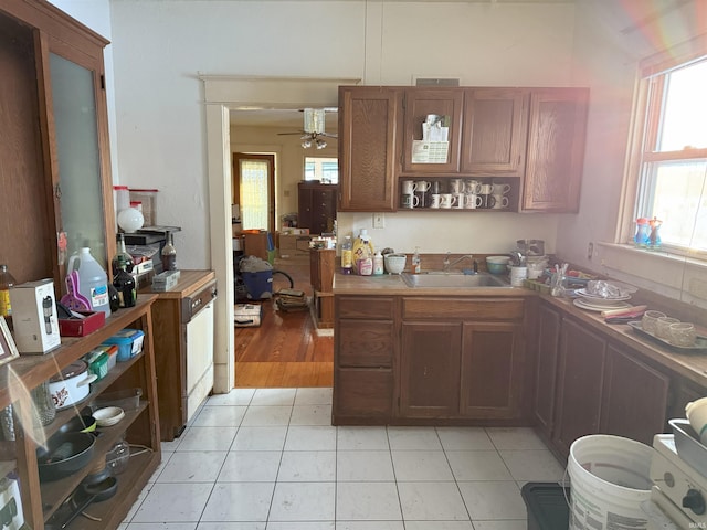 kitchen featuring open shelves, light tile patterned flooring, brown cabinets, and a sink