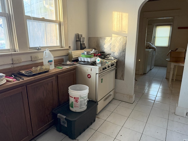 kitchen featuring arched walkways, light tile patterned floors, and white range with gas stovetop