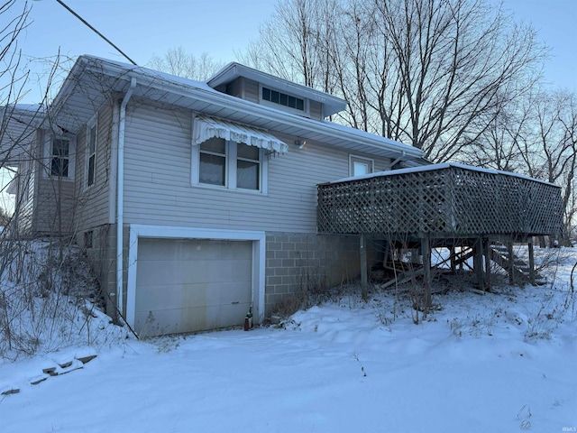 snow covered property featuring a deck and an attached garage