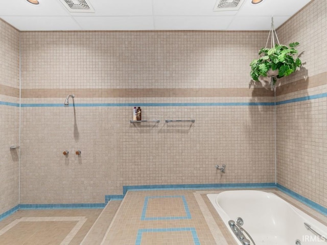 bathroom with visible vents, tiled shower, tile walls, and a relaxing tiled tub