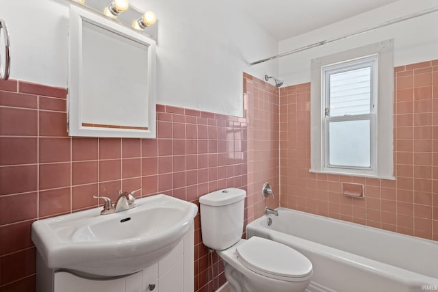 full bathroom featuring toilet, tile walls, wainscoting, washtub / shower combination, and vanity