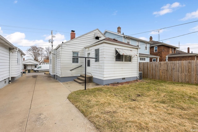 exterior space featuring fence, entry steps, concrete driveway, a lawn, and crawl space