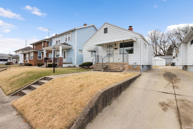 view of front of home with a front yard, a chimney, an outdoor structure, a detached garage, and a residential view