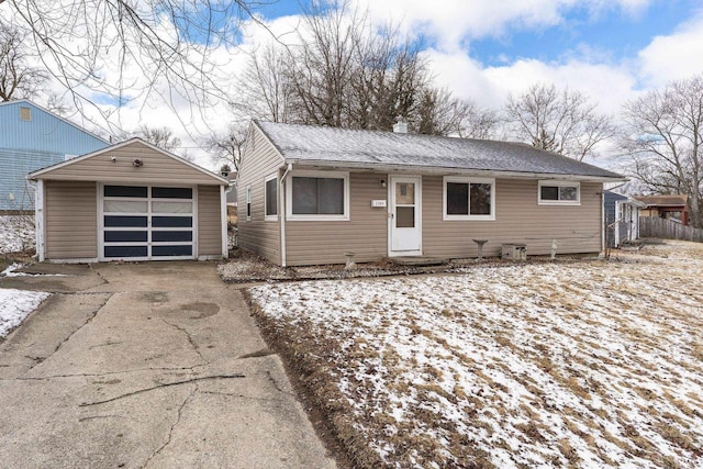 view of front of property with fence, roof with shingles, concrete driveway, an outdoor structure, and a detached garage