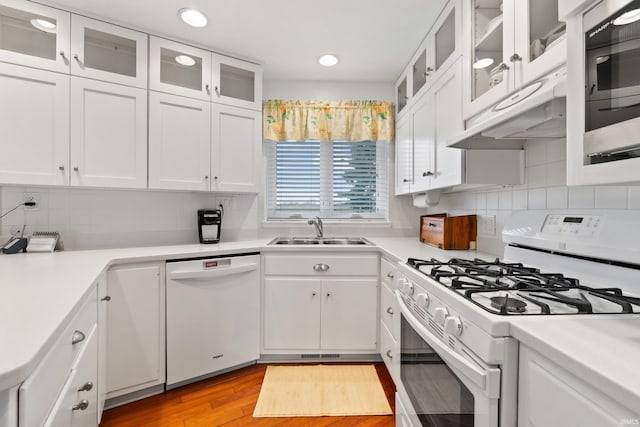 kitchen with a sink, white appliances, white cabinets, and light countertops