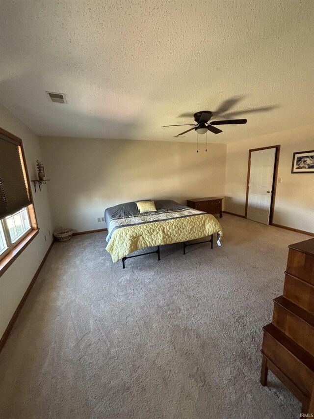 unfurnished bedroom with visible vents, baseboards, carpet, a textured ceiling, and a ceiling fan