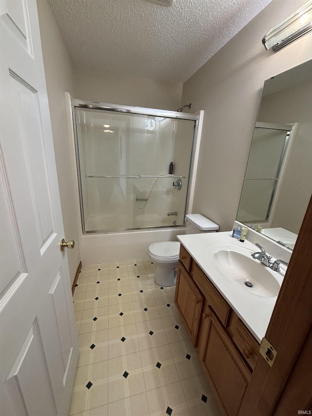 bathroom featuring tile patterned floors, toilet, a textured ceiling, shower / bath combination with glass door, and vanity